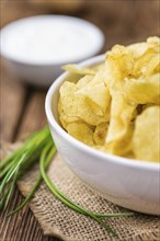 Potato Chips with Sour Cream taste as high detailed close-up shot on a vintage wooden table