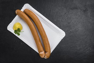 Sausages (Frankfurter) on a vintage slate slab (close-up shot, selective focus)