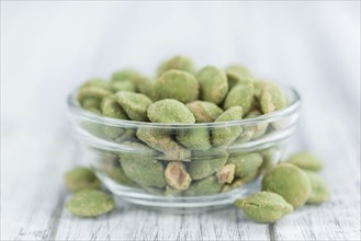 Peanuts (with Wasabi flavor) on an old wooden table as detailed close-up shot (selective focus)