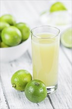 Fresh Lime Juice as high detailed close-up shot on a vintage wooden table (selective focus)