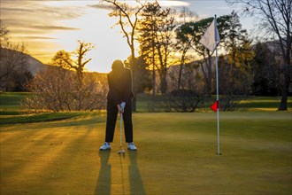 Female Golfer Concentration on the Putting Green on Golf Course in Sunset in Switzerland