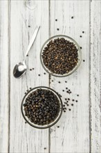 Preserved black Peppercorns on wooden background, selective focus, close-up shot