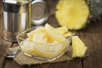 Preserved Pineapple Rings on an old wooden table as detailed close-up shot, selective focus