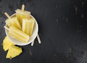 Some homemade Pineapple Popsicles (selective focus) on a rustic background