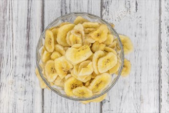 Homemade Dried Banana Chips on an wooden table as detailed close-up shot, selective focus