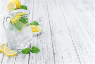 Lemonade (with Balm) as high detailed close-up shot on a vintage wooden table (selective focus)