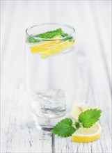 Lemonade (with Balm) as high detailed close-up shot on a vintage wooden table (selective focus)