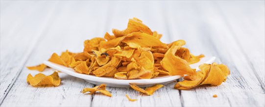 Sweet Potato Chips as high detailed close-up shot on a vintage wooden table, selective focus