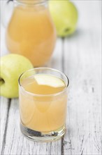 Homemade Apple Juice on an wooden table (selective focus) as detailed close-up shot