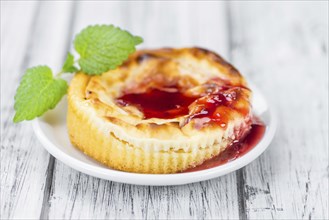 Fresh made Mini Cheesecake (with Sauce) on a vintage background (close-up shot)