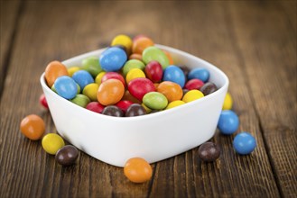 Cocolate coated Peanuts on rustic wooden background (close-up shot)