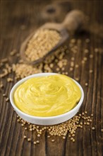 Mustard as high detailed close-up shot on a vintage wooden table (selective focus)