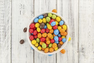 Cocolate coated Peanuts on rustic wooden background (close-up shot)