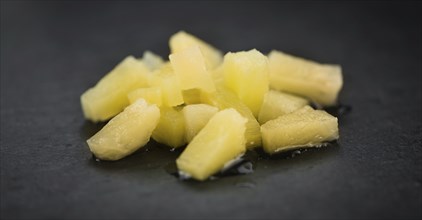 Portion of Preserved Pineapple (chopped) as detailed close up shot on a slate slab, selective focus