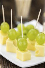 Cheese blocks with grapes as close-up shot (selective focus, partyfood)