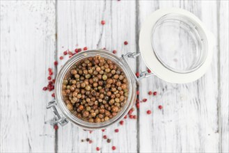 Preserved Pink Peppercorns on a vintage background as detailed close-up shot, selective focus