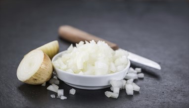 Portion of Chopped white onions as detailed close up shot on a slate slab, selective focus