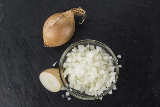 Some White Onions (dices) on a slate slab as detailed close-up shot, selective focus