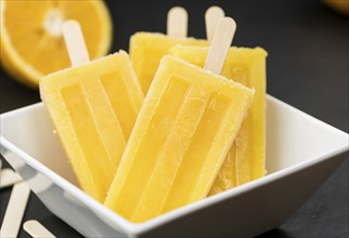 Some homemade orange popsicles (selective focus) on a vintage background