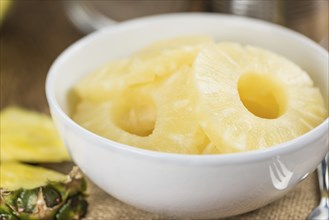 Preserved Pineapple Rings on an old wooden table as detailed close-up shot, selective focus