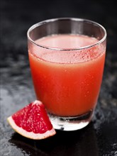 Some freshly squeezed Grapefruit Juice on a vintage background (close-up shot, selective focus)