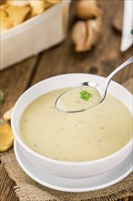 Creamy Chanterelle Soup on an old wooden table as detailed close-up shot, selective focus