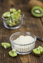 Bowl with fresh made Kiwi powder (close-up shot, selective focus) on an old wooden table