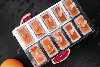 Some homemade Grapefruit Popsicles (with some fresh fruits) as close-up shot (selective focus)