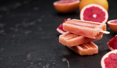 Vintage slate slab with some freshly made Grapefruit Popsicles (selective focus, close-up shot)