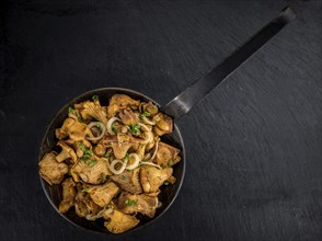 Portion of Fried Chanterelles on a rustic slate slab, selective focus, close-up shot