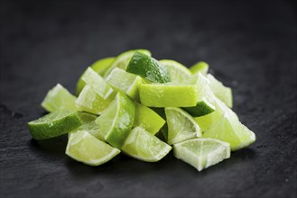 Portion of Sliced Limes as detailed close up shot on a slate slab (selective focus)