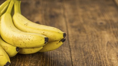 Whole Bananas as high detailed close-up shot on a vintage wooden table, selective focus