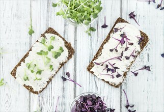 An old wooden table with healthy food (slice of bread, cream cheese and fresh cutted cress),