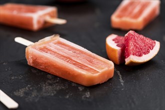 Vintage slate slab with some freshly made Grapefruit Popsicles (selective focus, close-up shot)