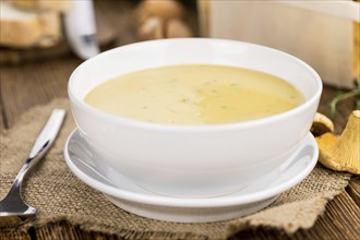 Chanterelle Soup as high detailed close-up shot on a vintage wooden table, selective focus