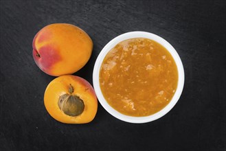 Portion of Apricot Jam as detailed close up shot on a slate slab (selective focus)