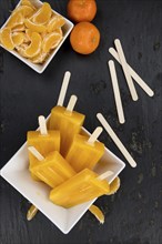 Slate slab with homemade Tangerine Popsicles (selective focus) as detailed close-up shot