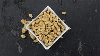 Roasted and salted Peanuts on vintage background (close-up shot, selective focus)