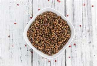 Fresh made Pink Peppercorns (preserved) on an old and rustic wooden table, selective focus,