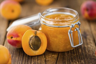 Apricot Jam as high detailed close-up shot on a vintage wooden table (selective focus)