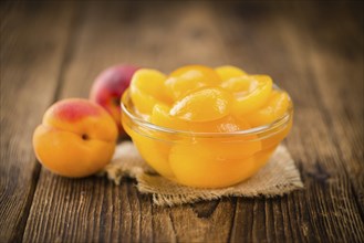 Canned Apricots on an old wooden table as detailed close-up shot (selective focus)