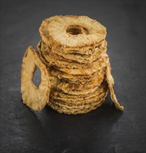 Portion of Dried Pineapple Rings on a rustic slate slab, selective focus, close-up shot