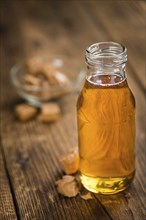 Caramel Syrup as high detailed close-up shot on a vintage wooden table (selective focus)