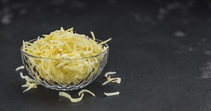 Homemade Grated Cheese (close-up shot) on a vintage slate slab