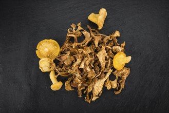 Portion of Dried Chanterelles as detailed close up shot on a slate slab, selective focus