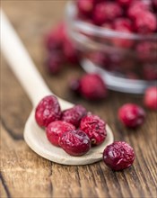 Healthy Cranberries (dried) on a wooden table as detailed close-up shot (selective focus)