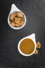 Portion of Caramel Sauce as detailed close up shot on a slate slab (selective focus)