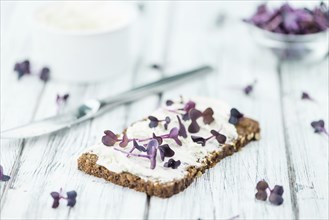 Slice of wholemeal bread with fresh cutted cress and cream cheese on an old wooden table (selective