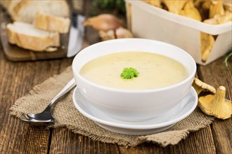 Creamy Chanterelle Soup on an old wooden table as detailed close-up shot, selective focus