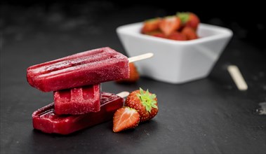 Slate slab with homemade Strawberry Popsicles (selective focus, close-up shot)